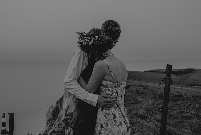 couple hugging each other standing on the cliff