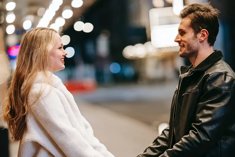 couple looking at each other while standing on street at night
