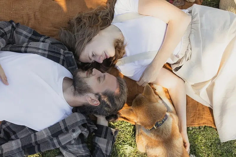 couple lying on brown blanket looking at each other