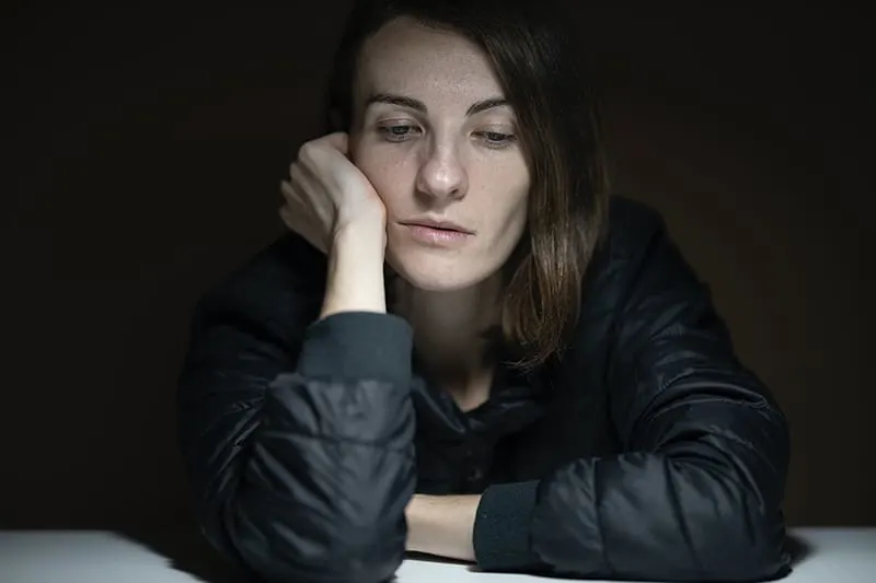 depressed woman looking down while sitting at the table