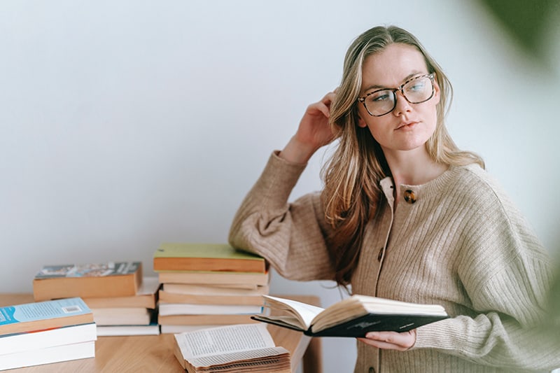 distracted woman holding a book and looking aside