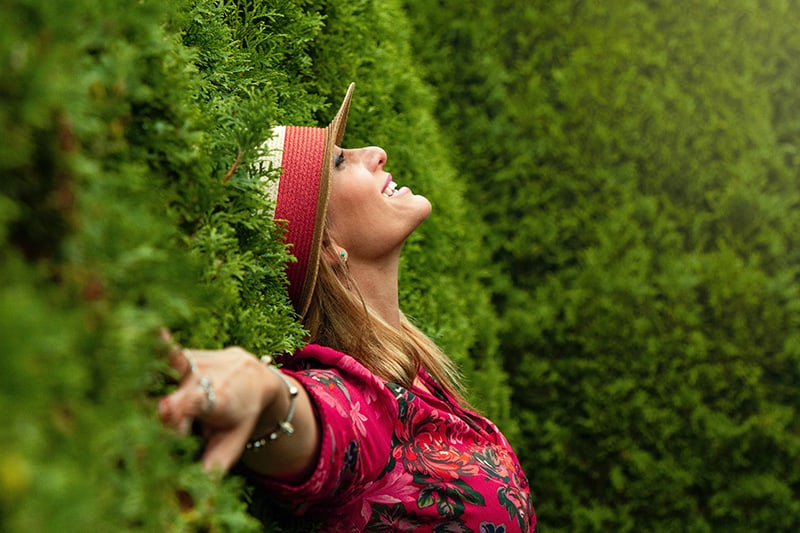 donna felice appoggiata agli alberi che allarga le mani