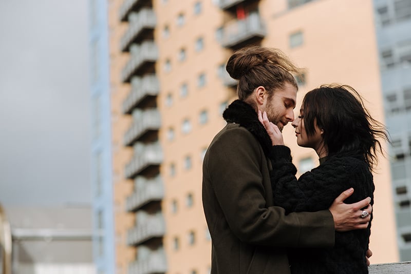 loving couple about to kiss standing in front of the skyscraper