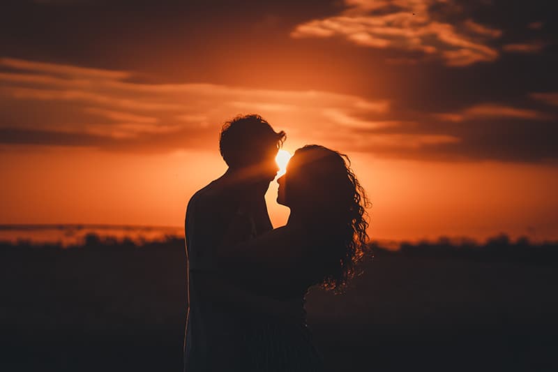 casal amoroso prestes a beijar-se ao pôr do sol