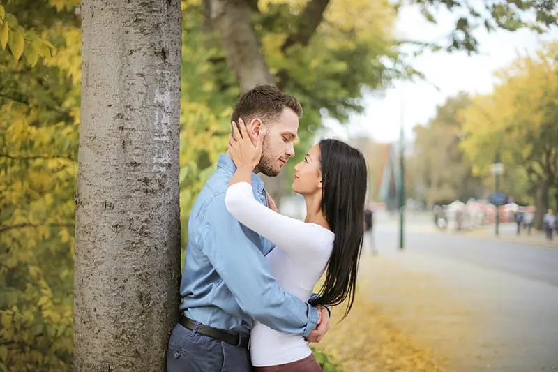 loving couple embracing each other standing near the tree