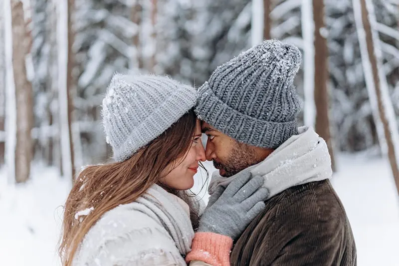 loving couple facing each other standing in snow and hugging