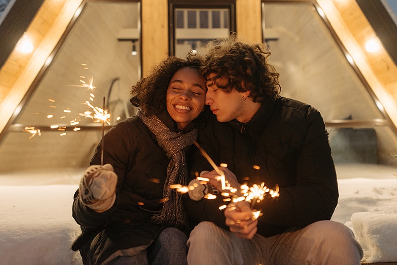 loving couple holding a fire sparkles sitting on the snow
