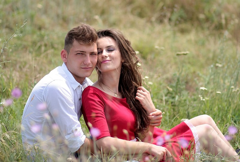 coppia di innamorati che si abbracciano seduti in un campo d'erba