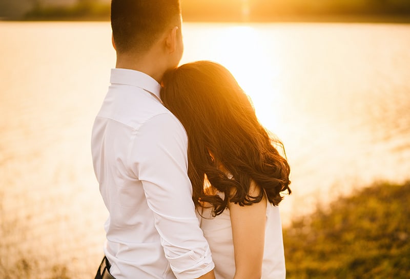 loving couple hugging and holding hands during sunset