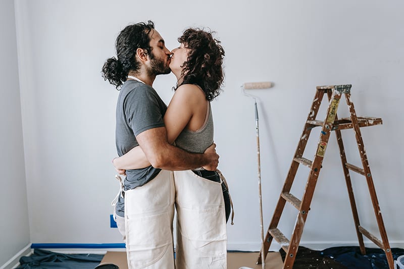 casal amoroso a beijar-se enquanto adaptam o apartamento juntos