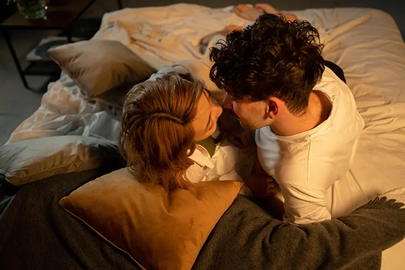 man and a woman about to kiss lying in the bed
