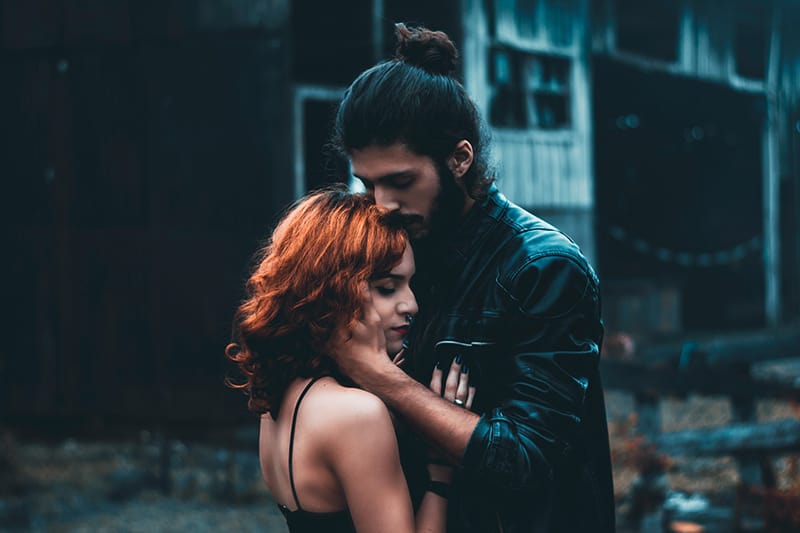 man and woman with closed eyes embracing each other standing on the street