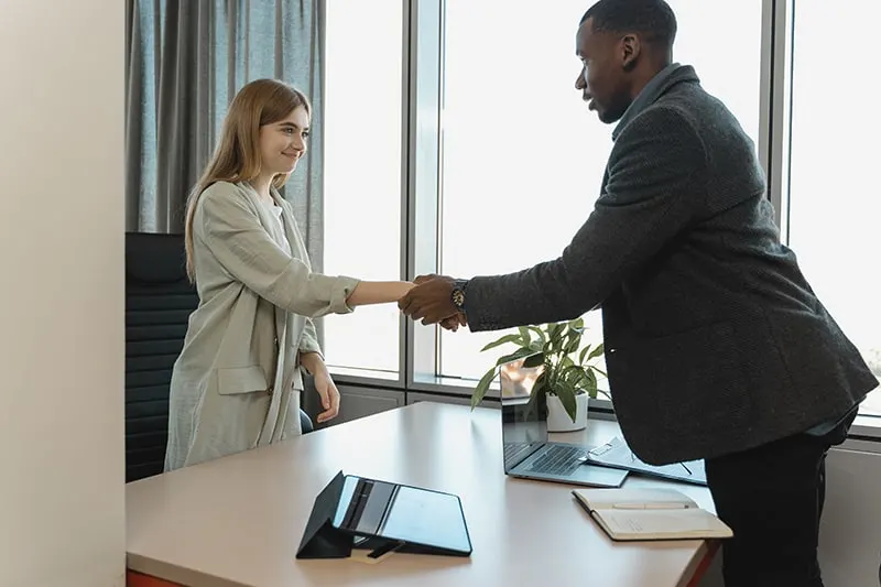 man hiring a woman and shaking hands with her in the office