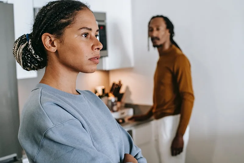 offended woman standing in the kitchen in front of her husband