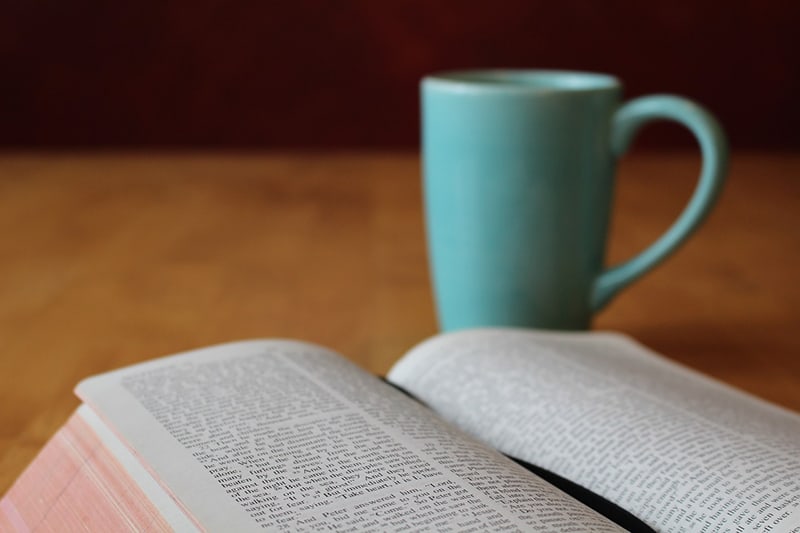 opened book bible beside the blue mug