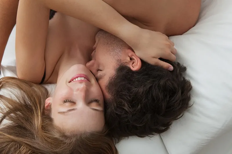  romantic couple hugging and kissing laying on a bed