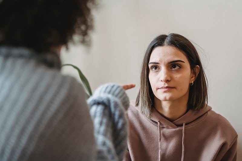 donna seria che guarda la persona che le punta il dito contro durante la conversazione