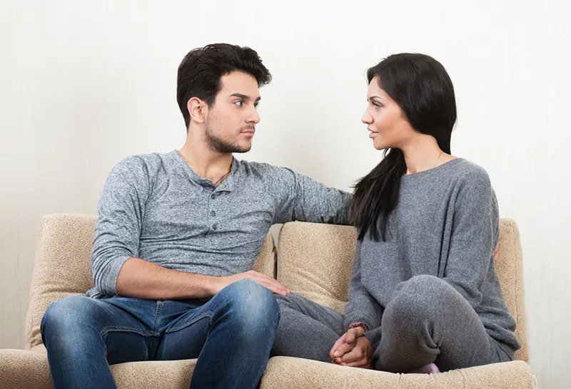 serious woman talking with her boyfriend while sitting on the sofa together