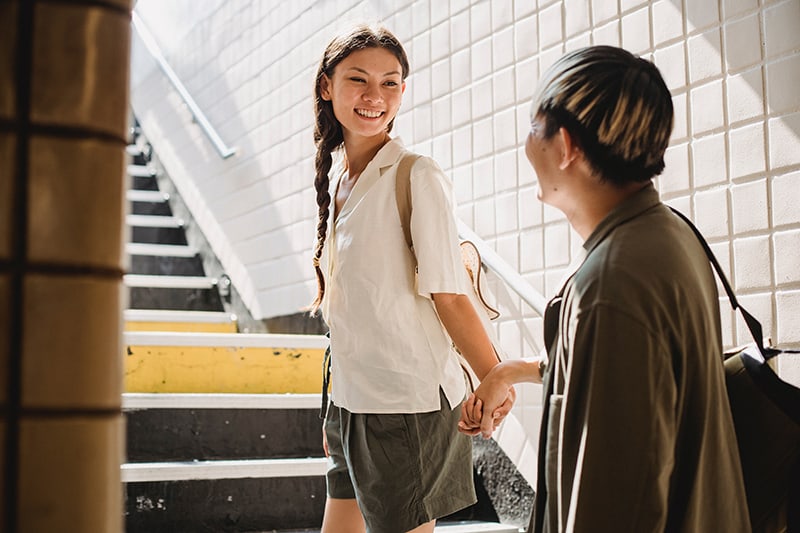 smiling woman holding mans hand looking at each other in pasway