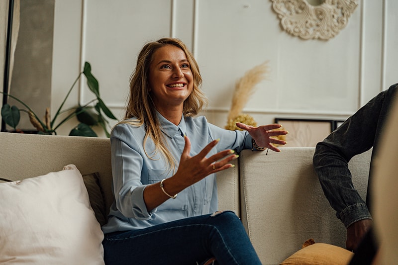 smiling woman talking with someone sitting on the couch