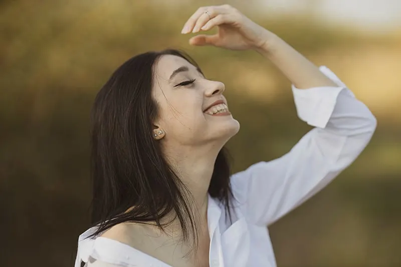 smiling woman with eyes closed facing the sky