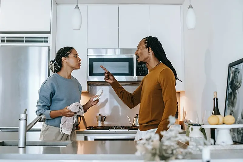 spouses arguing in the kitchen while woman doing dishes