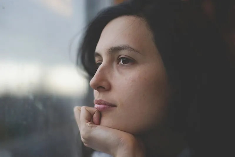 thoughtful woman looking through window