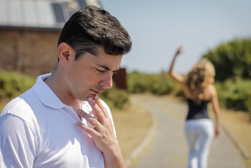 unhappy frustrated man standing alone while angry wife leaving him