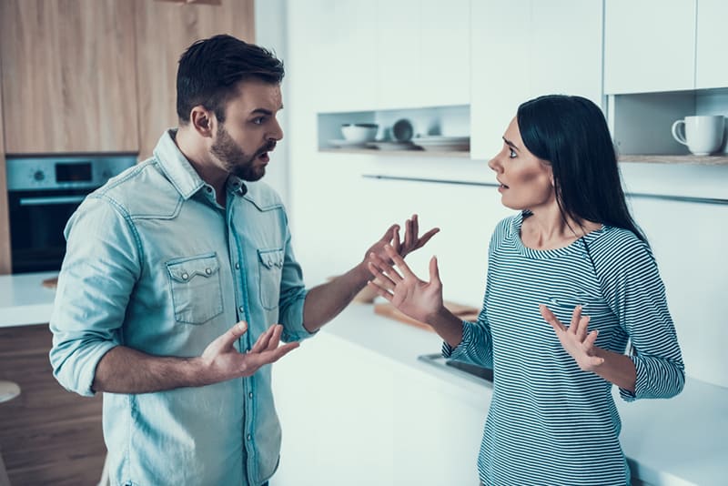 upset man yelling on his offended wife in the kitchen