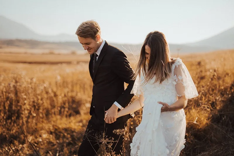 wedding couple holding hands walking in the field