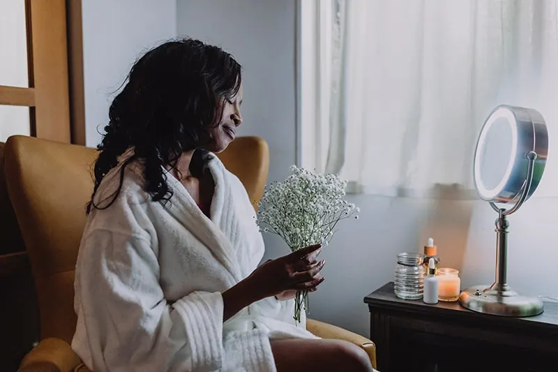 woman holding white flowers sitting at home in the bathrobe