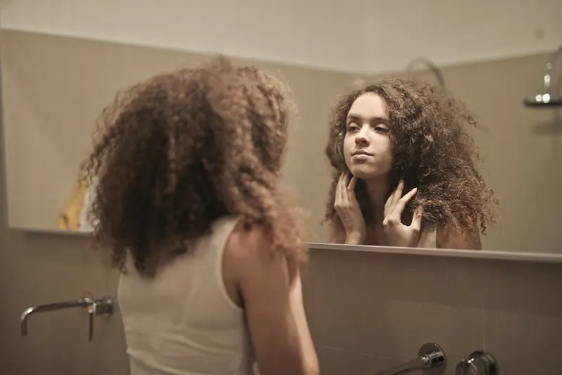 woman looking herself in the mirror in the bathroom