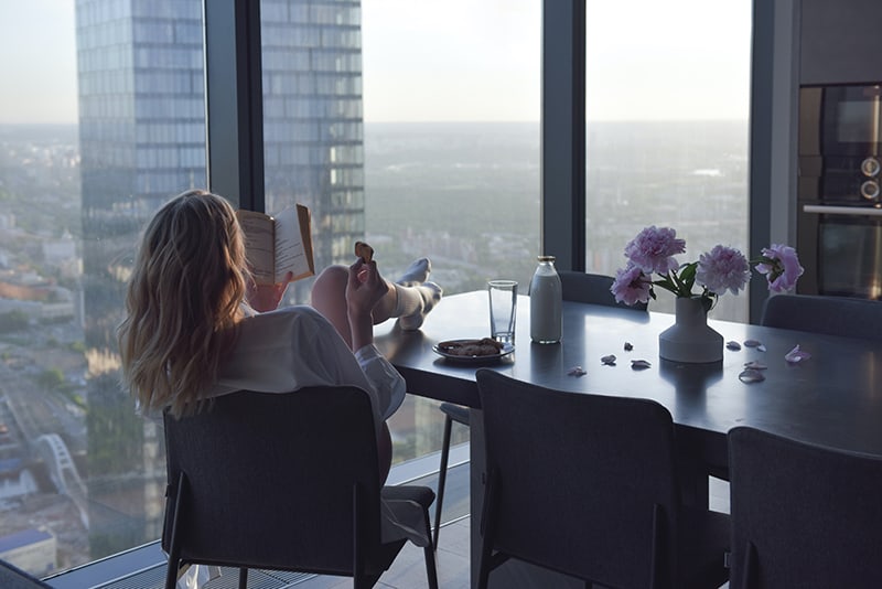 woman reading a book with her feet on the table