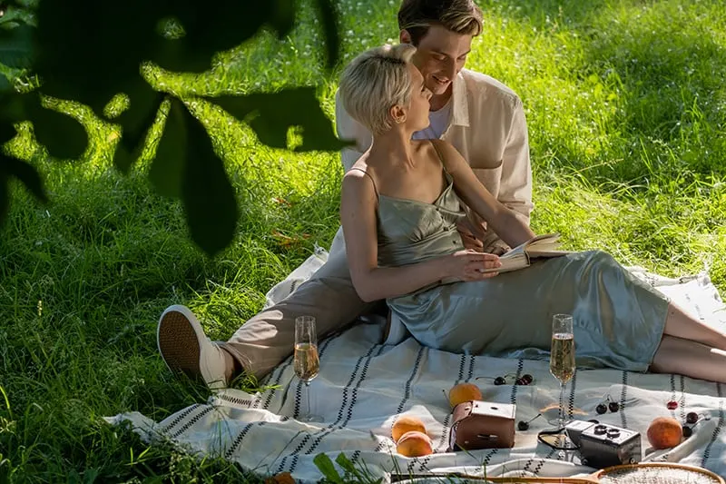 woman reading love poetry to her boyfriend on romantic picnic