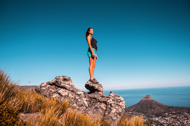 mulher de pé sobre uma pedra sob o céu azul