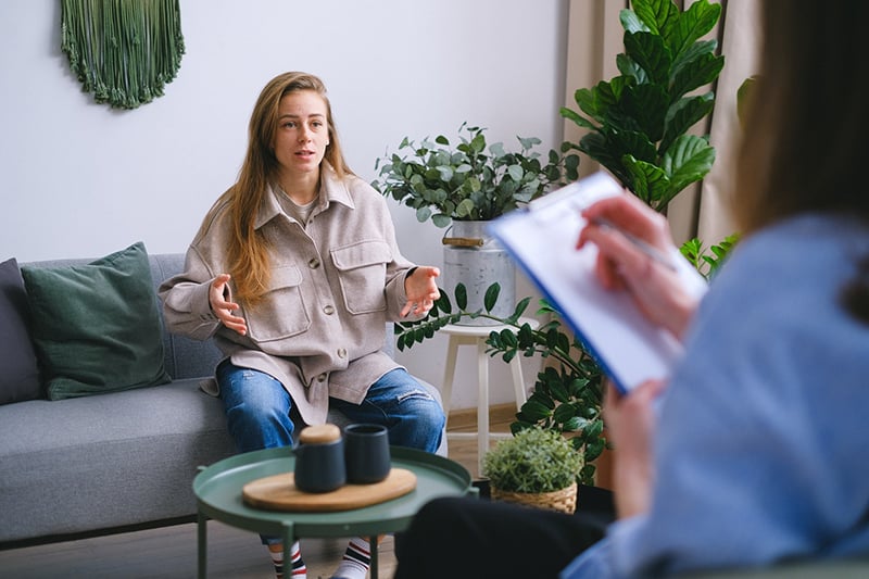 mulher a falar com o psicólogo enquanto está sentada no sofá