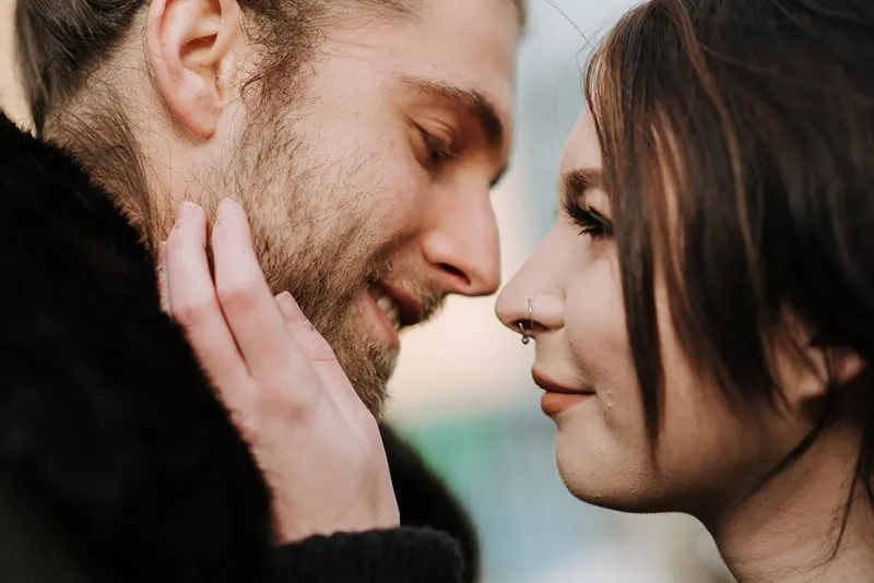 woman touching a face of smiling boyfriend about to kiss her