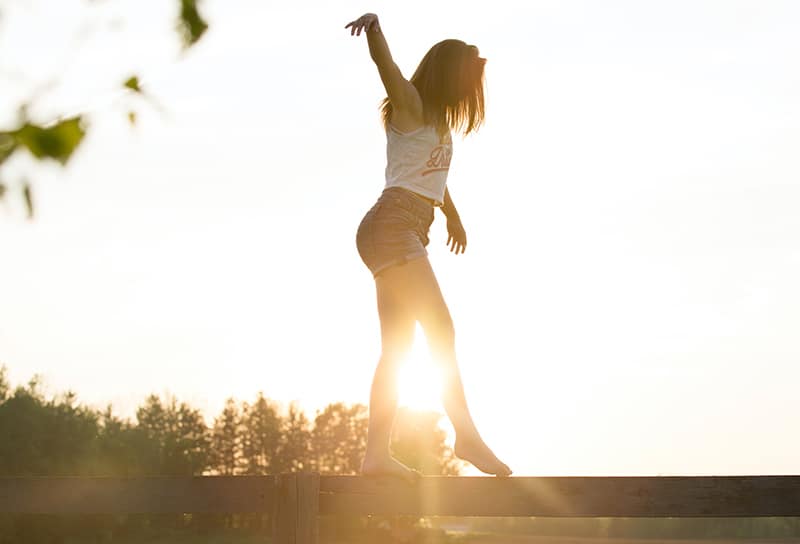 mujer caminando por la valla durante la puesta de sol