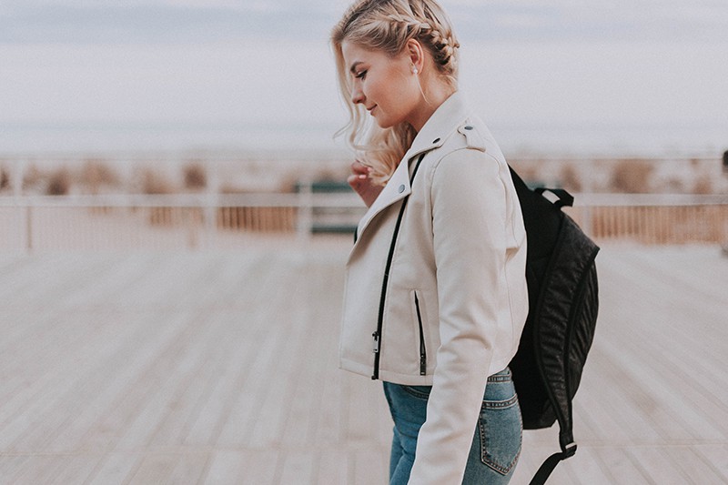 woman with backpack looking down standing on wooden terrace