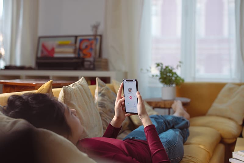 women using dating app while lying on the couch