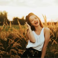 a smiling woman stands in a field of grain