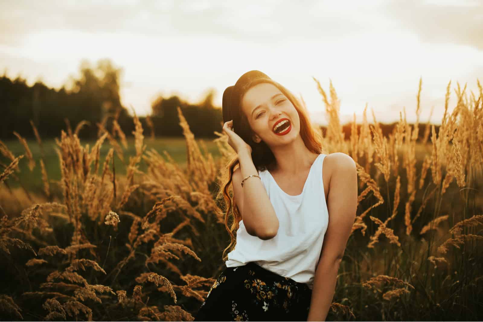 a smiling woman stands in a field of grain