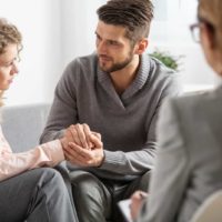 un hombre y una mujer se cogen de la mano mientras hablan con un médico