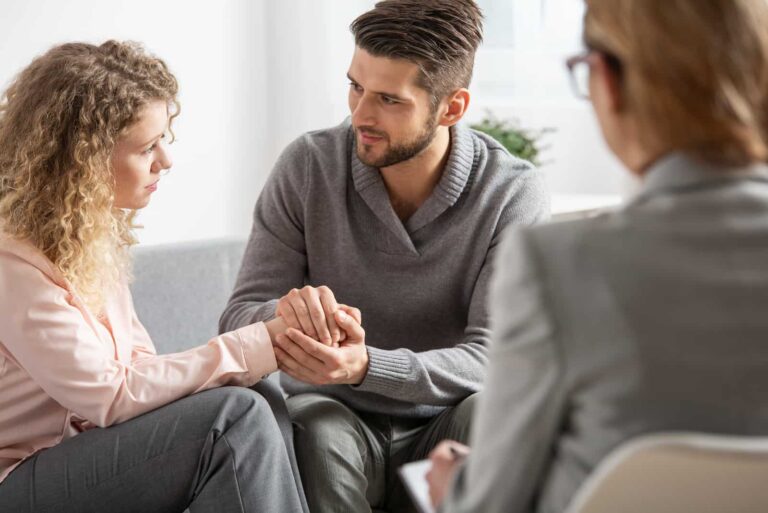 a man and a woman hold hands while talking to a doctor