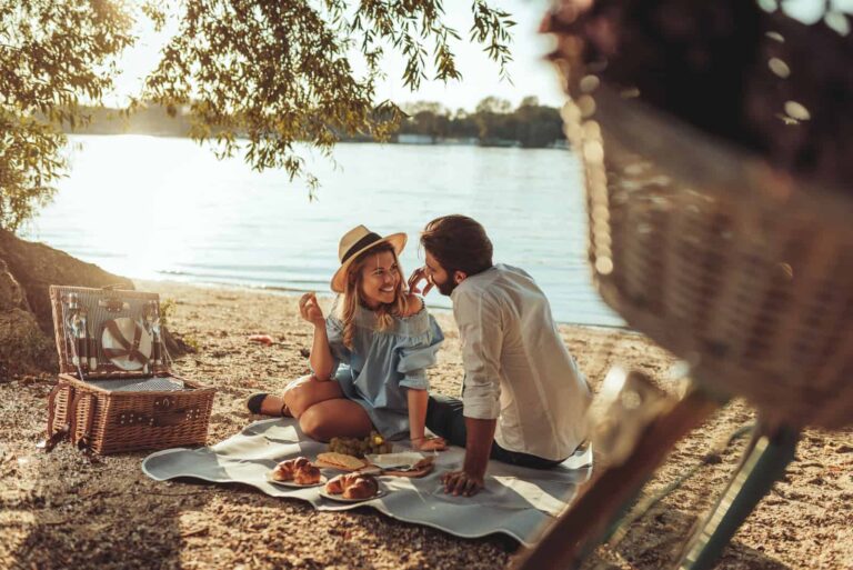 un hombre y una mujer sonrientes desayunando en la playa