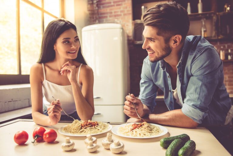 a man and a woman sit in the kitchen and eat