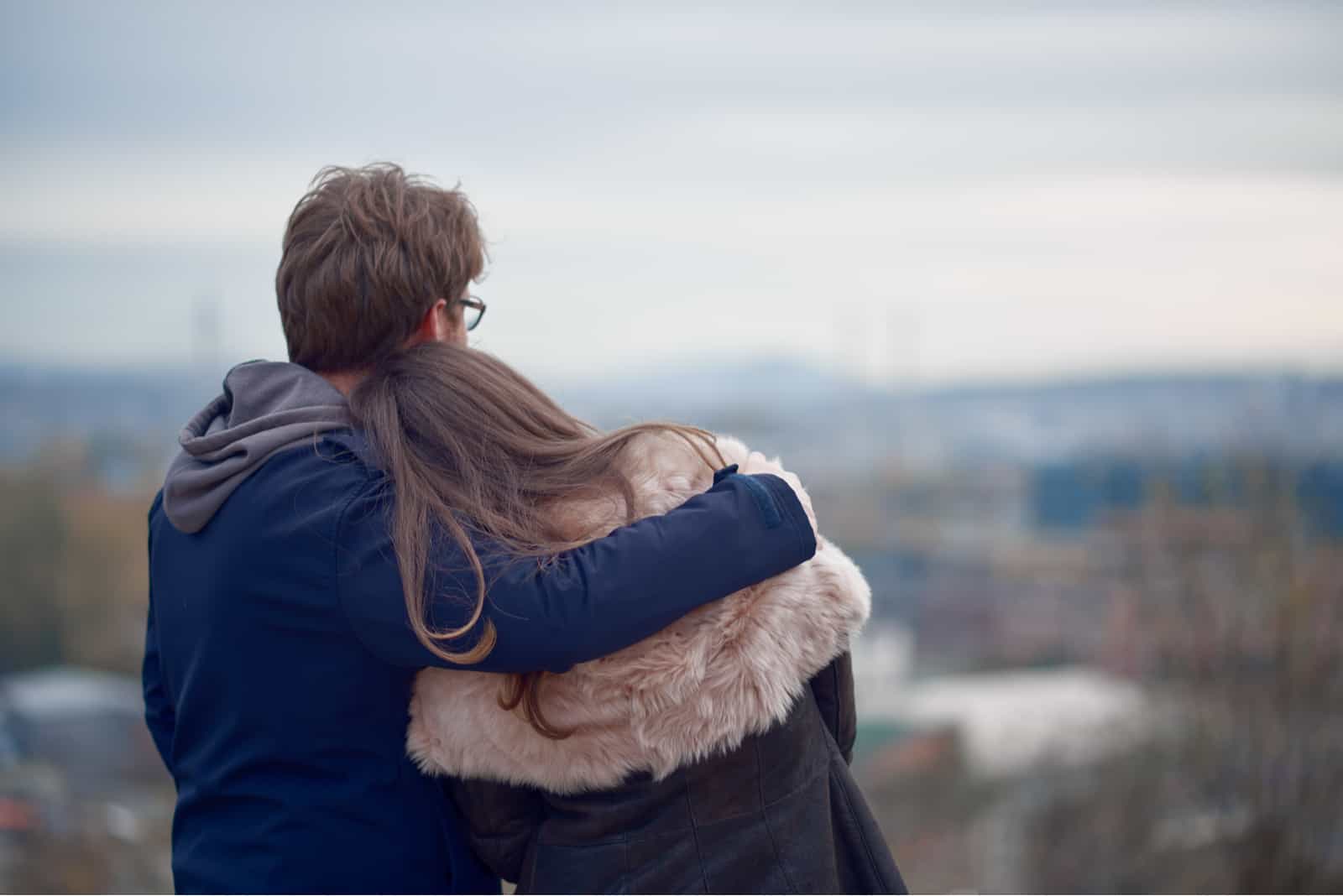 Pareja abrazándose y mirando al horizonte en otoño