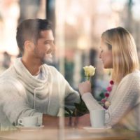 un hombre y una mujer se sientan a la mesa y charlan tomando un café