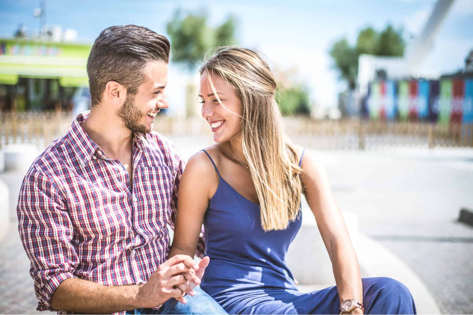 a smiling man and woman sit and hold hands