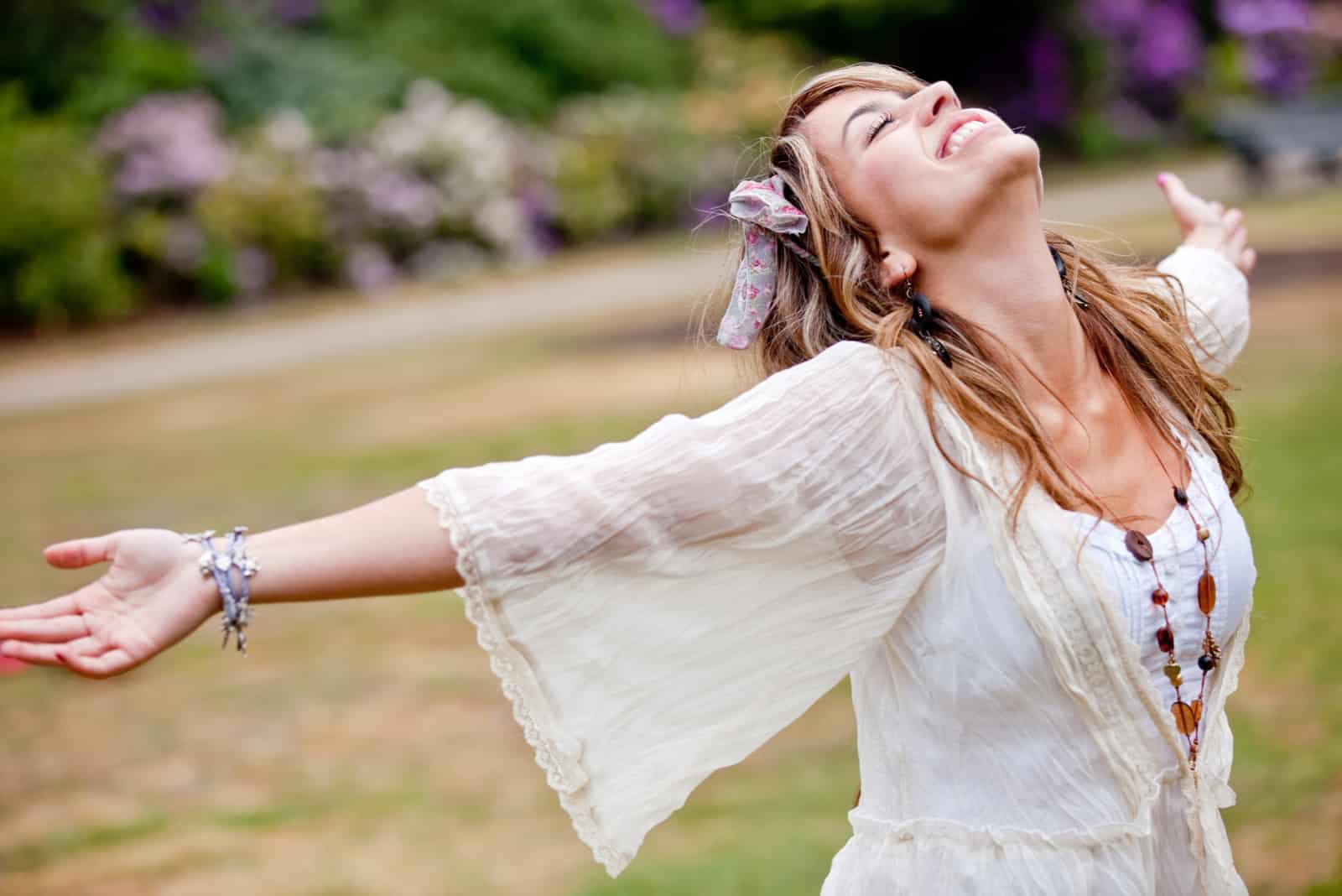 a beautiful woman in a white dress stands with her arms outstretched